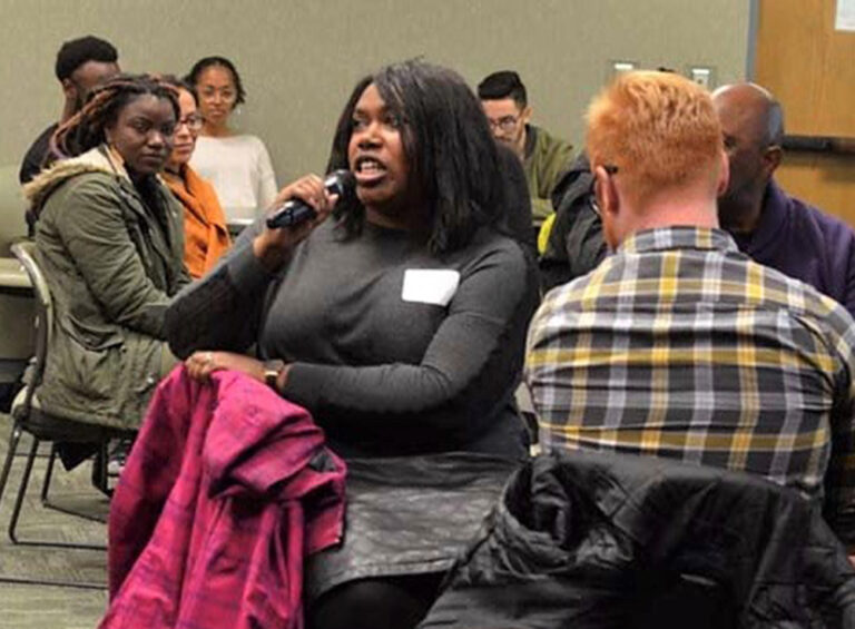 A participant speaks into a microphone during a CCDE listening party