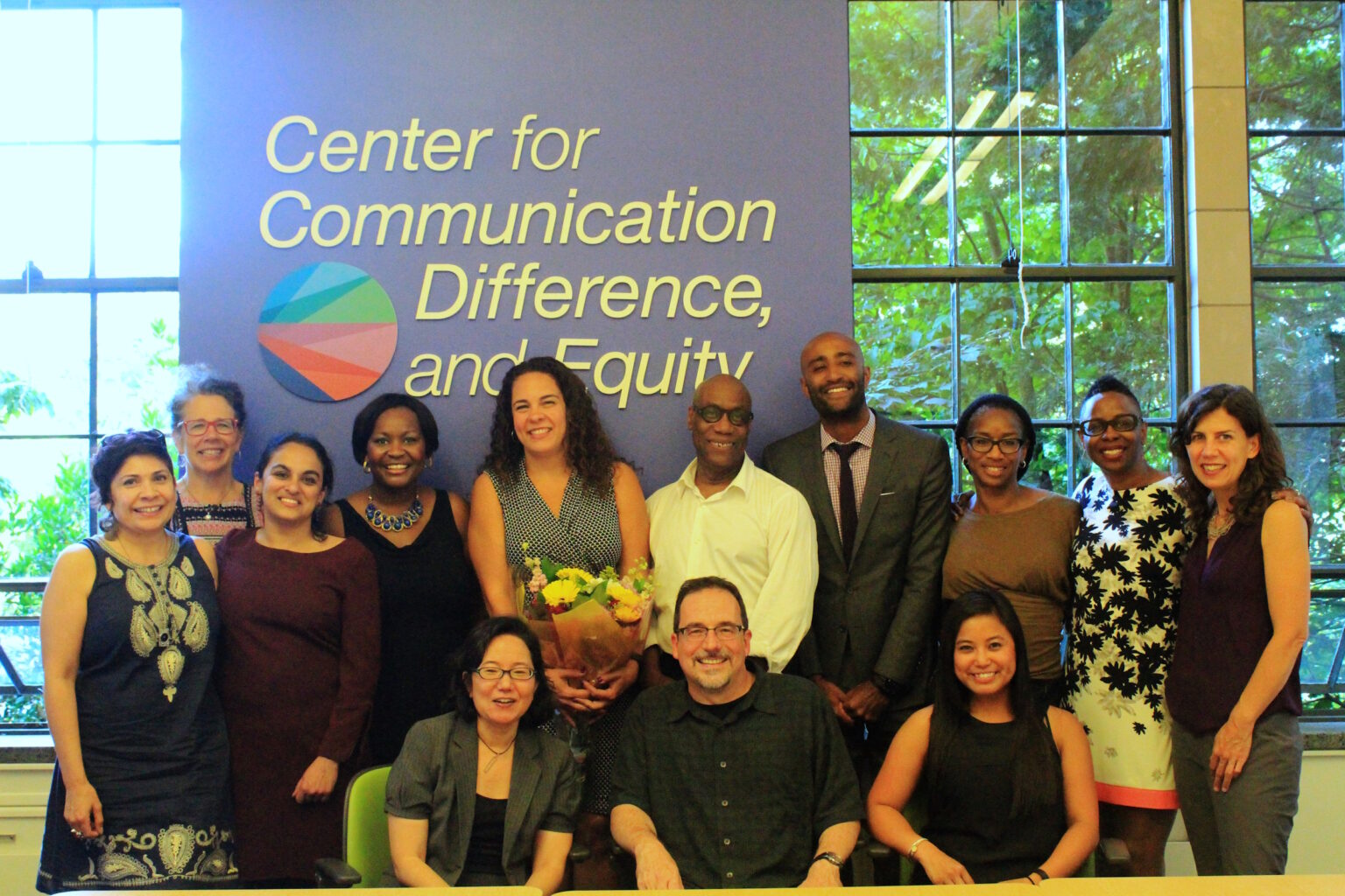 CCDE members posed together in front of a Center for Communication, Difference, and Equity banner